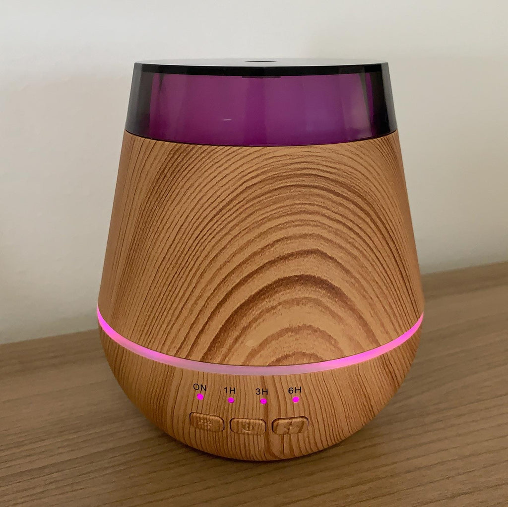 Wooden diffuser with purple accents on a wooden surface