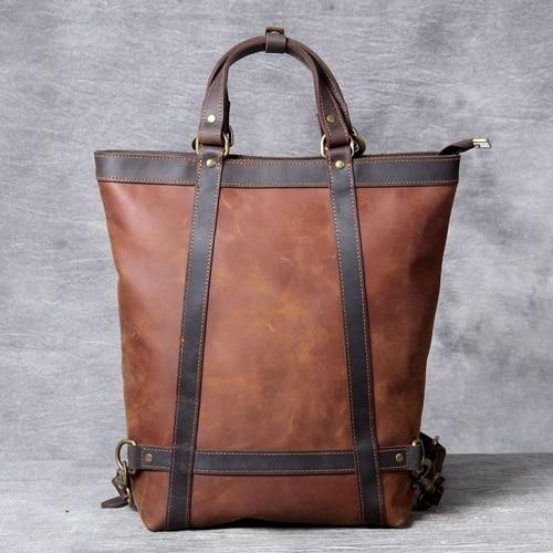 Brown leather tote bag with straps on a gray background