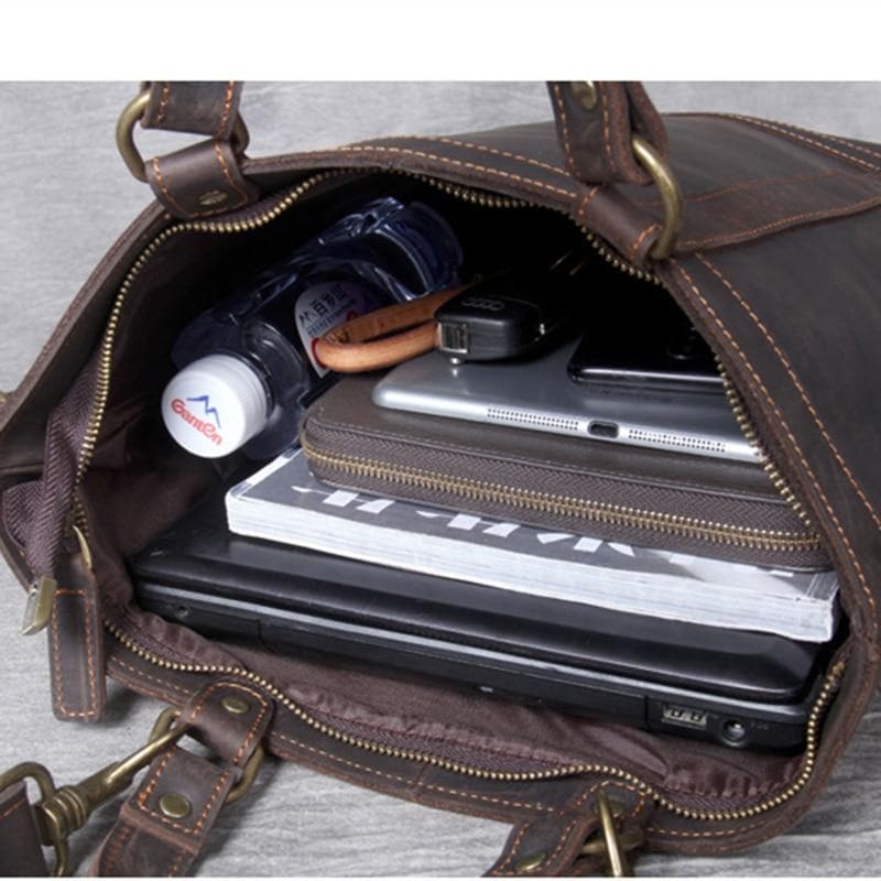 Brown leather briefcase with items like a laptop, phone, and notebook inside.