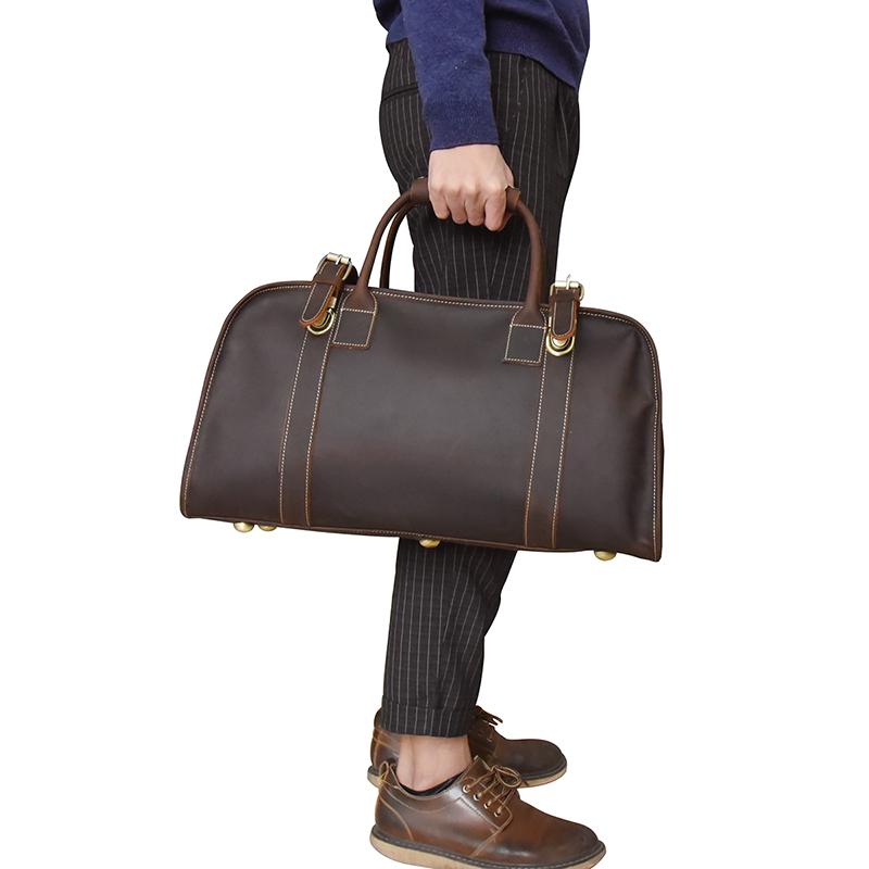 Man holding a premium brown leather duffle bag with gold hardware, Alpine-Nordic style